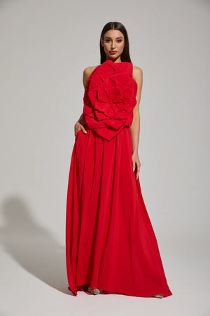 Woman wearing a red evening gown with floral details on a white background