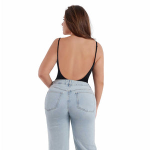 Woman wearing a black open-back top and light blue jeans on a white background
