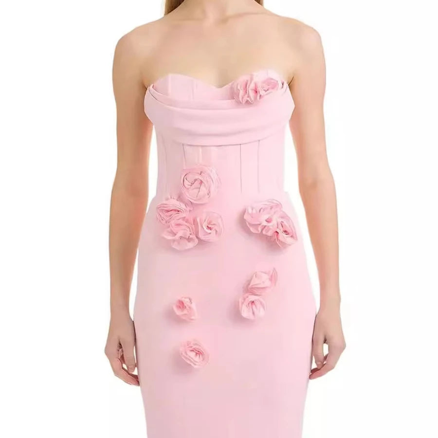 Woman wearing a pink strapless gown with floral embellishments on a white background